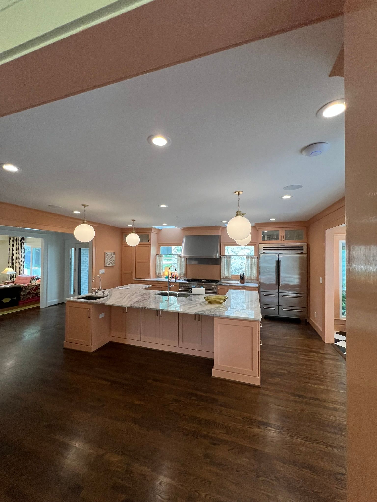 Spacious modern kitchen with dark wood floors, central island, white cabinets, and pendant lights
