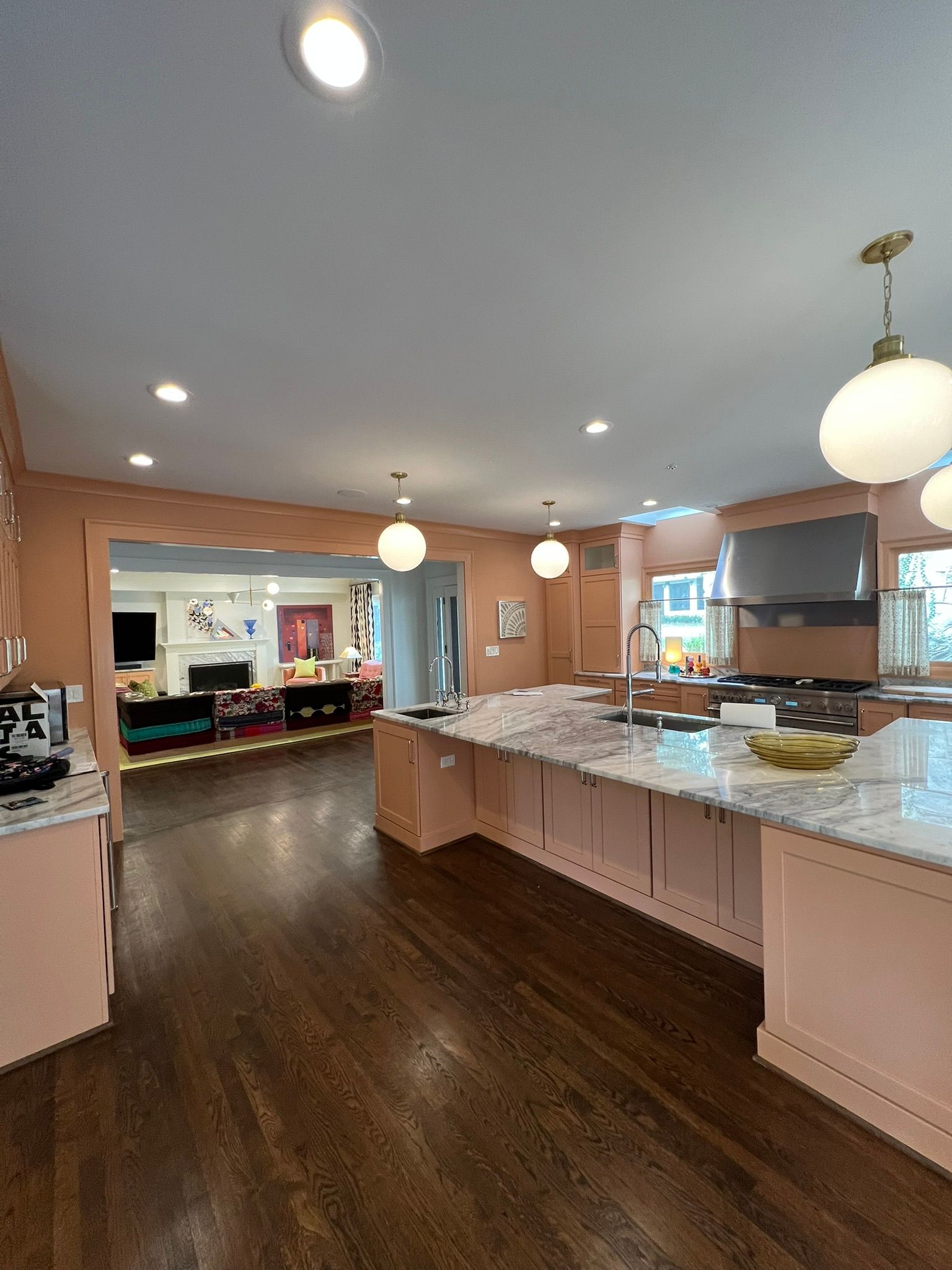 Bright kitchen with dark wood floors, white island, pendant lights, and granite counters