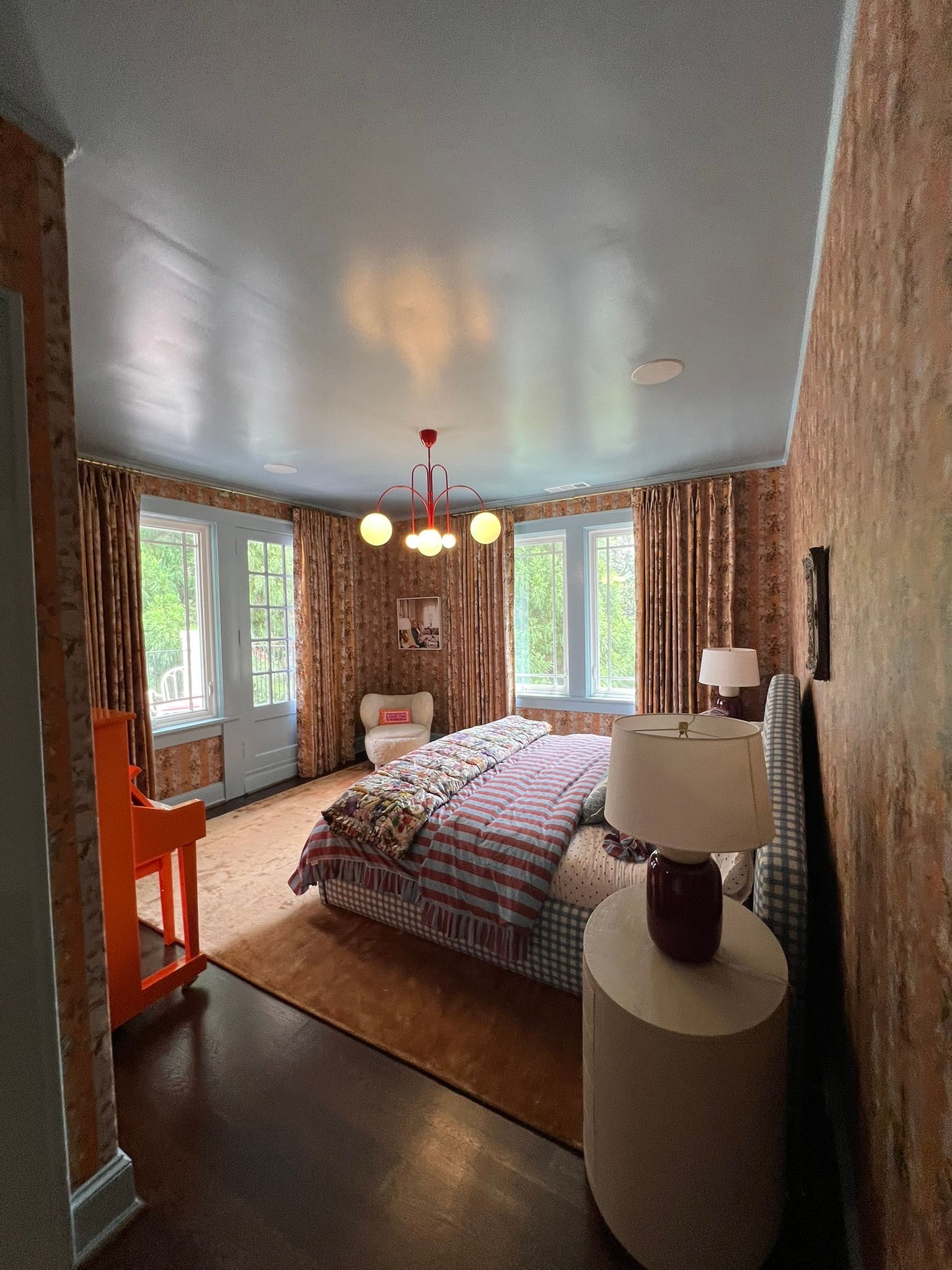 Cozy bedroom with a bed, pendant light, large windows, and patterned curtains