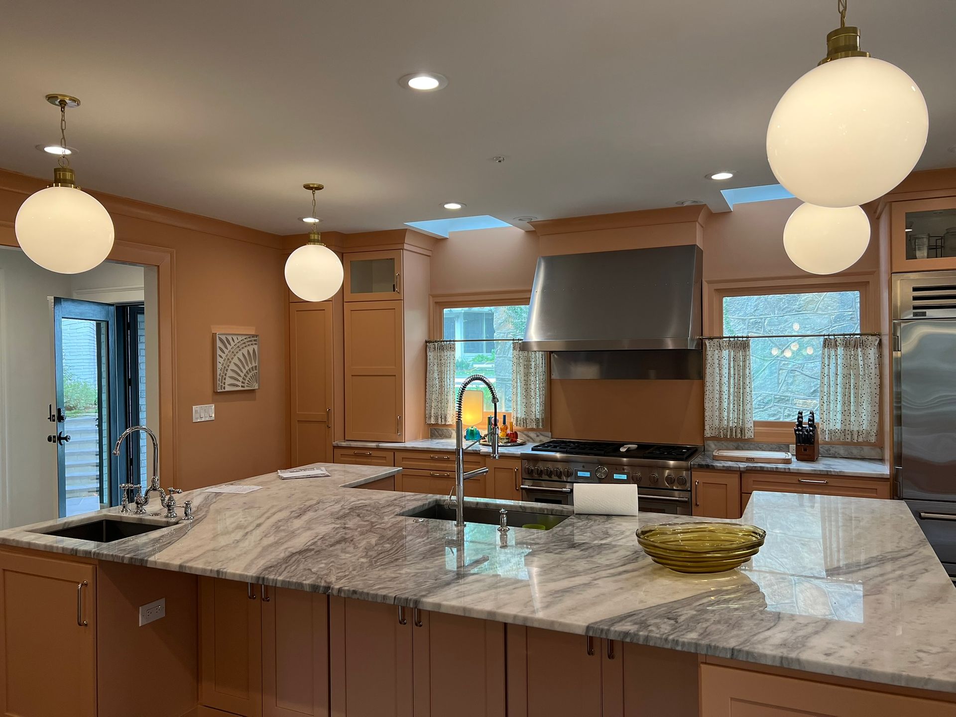 Modern kitchen with large island, granite counters, wood cabinets, and hanging globe pendant lights.