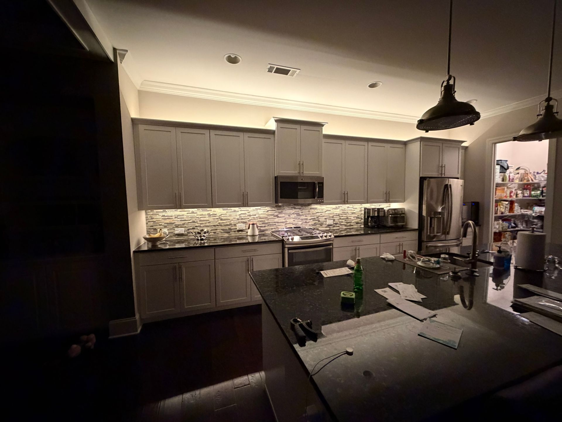 Modern kitchen with gray cabinets, black island, pendant lights, and stainless-steel appliances