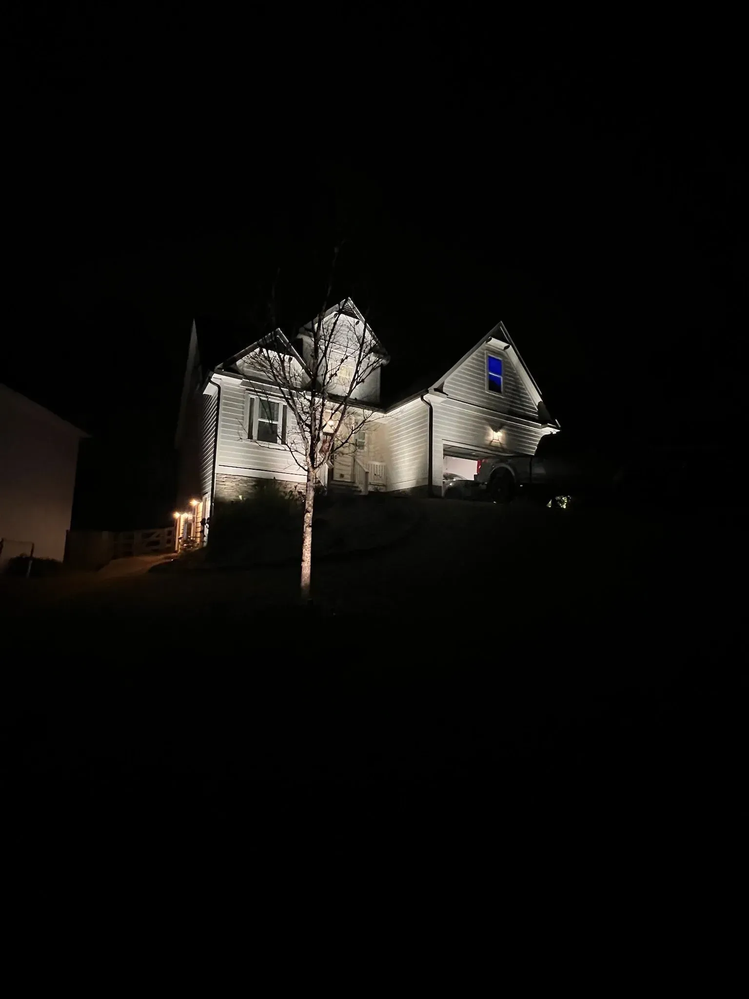 Illuminated house at night with bright white Christmas lights against a dark sky