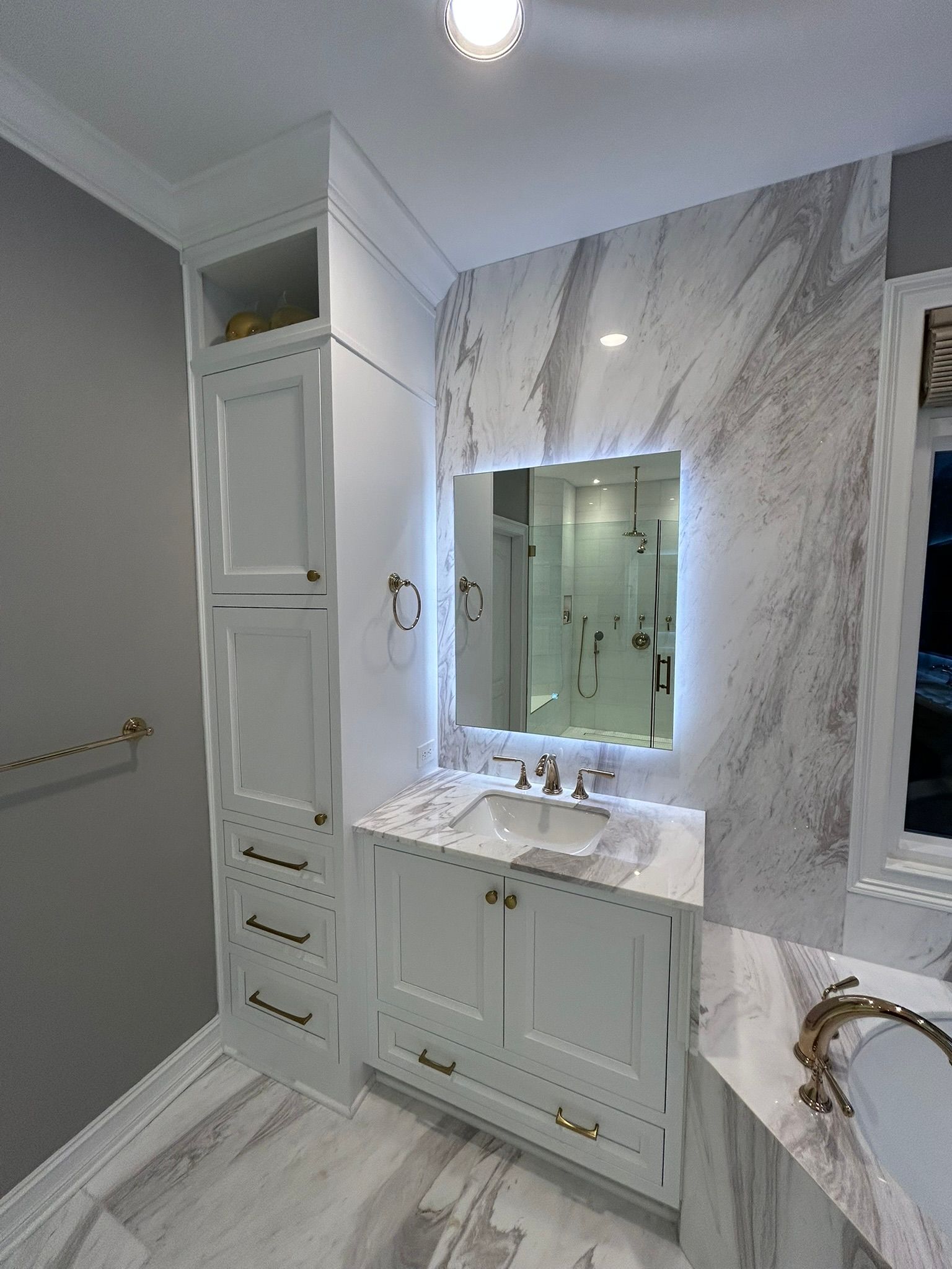 Elegant white bathroom vanity with marble walls, mirror, sink, and built-in cabinets