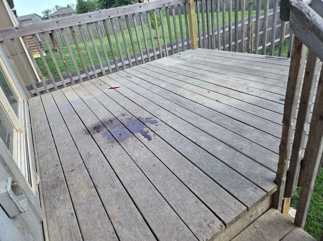 A wooden backyard deck with a dark stain on the floorboards and a small bird standing nearby.
