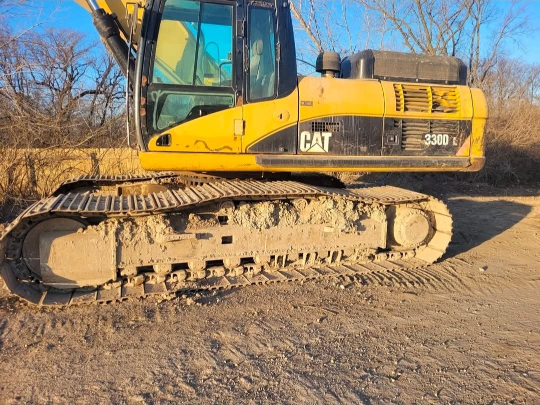 A yellow Caterpillar 336D excavator parked on dirt, viewed from the side with muddy tracks visible.