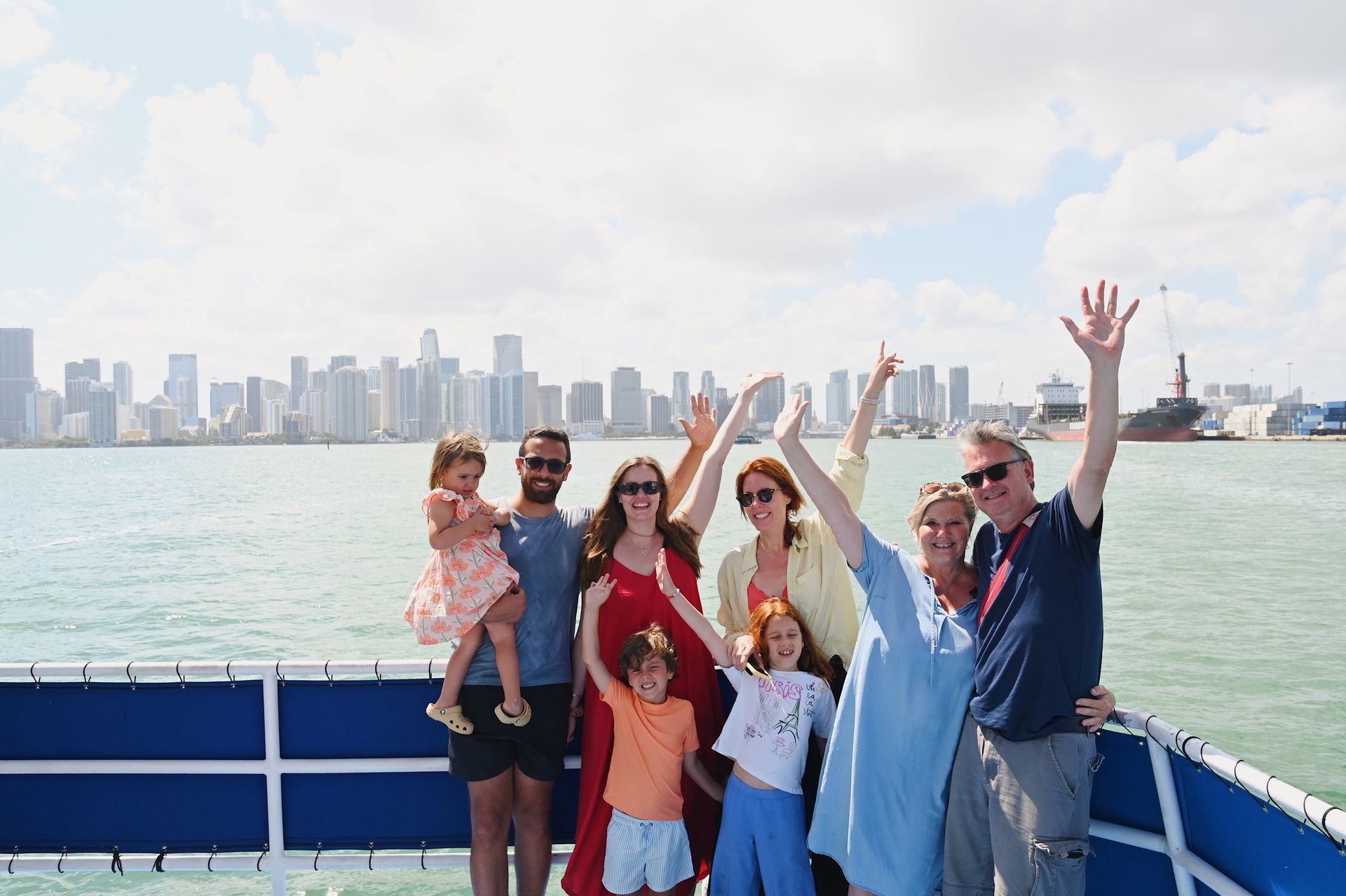 Happy family with hands up smiling enjoying the Miami Boat tours with the Miami Skyline in the background
