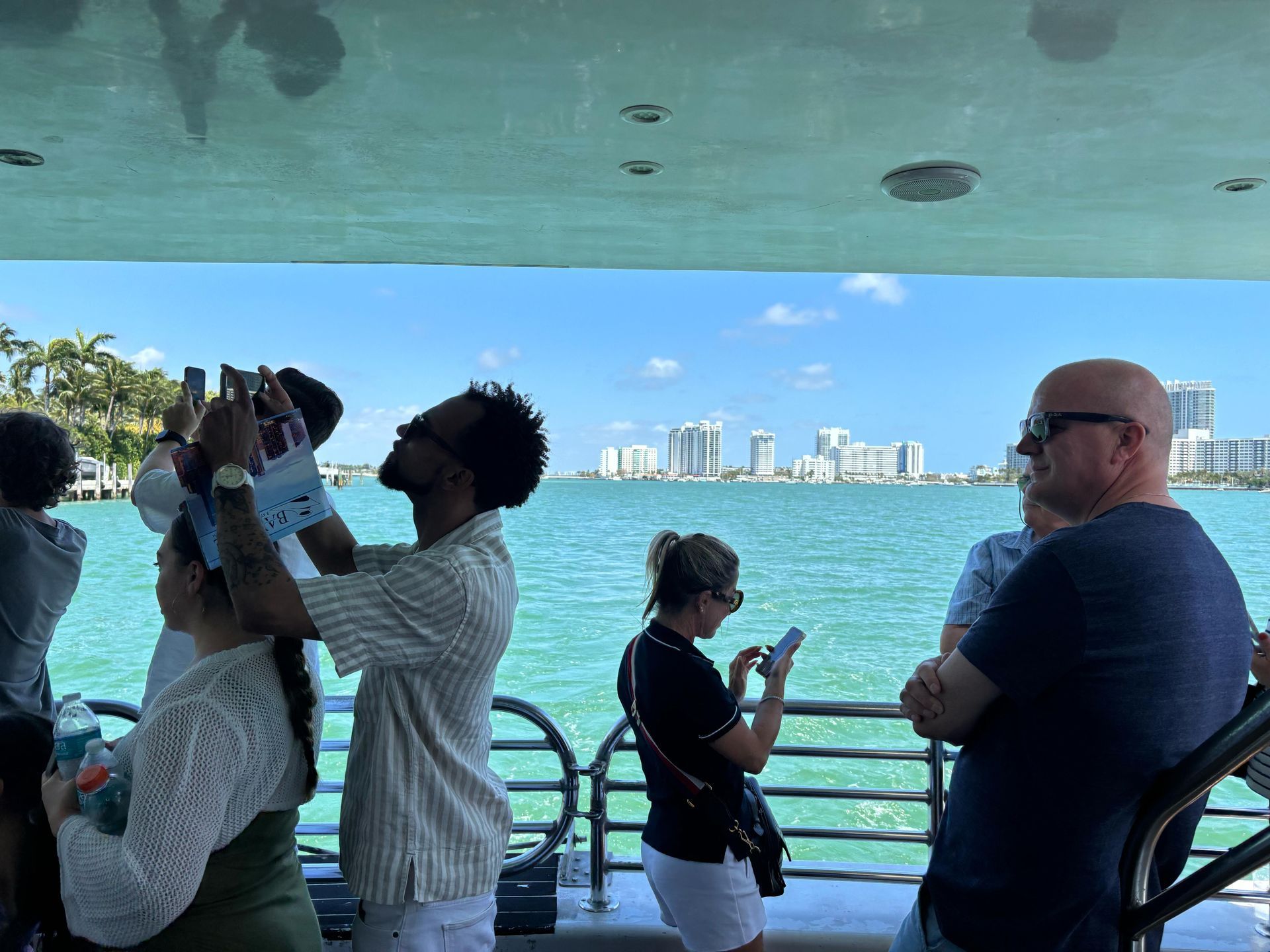 Tourists taking photos on the Miami Boat Tour with views of Star Island and Miami Beach in the background
