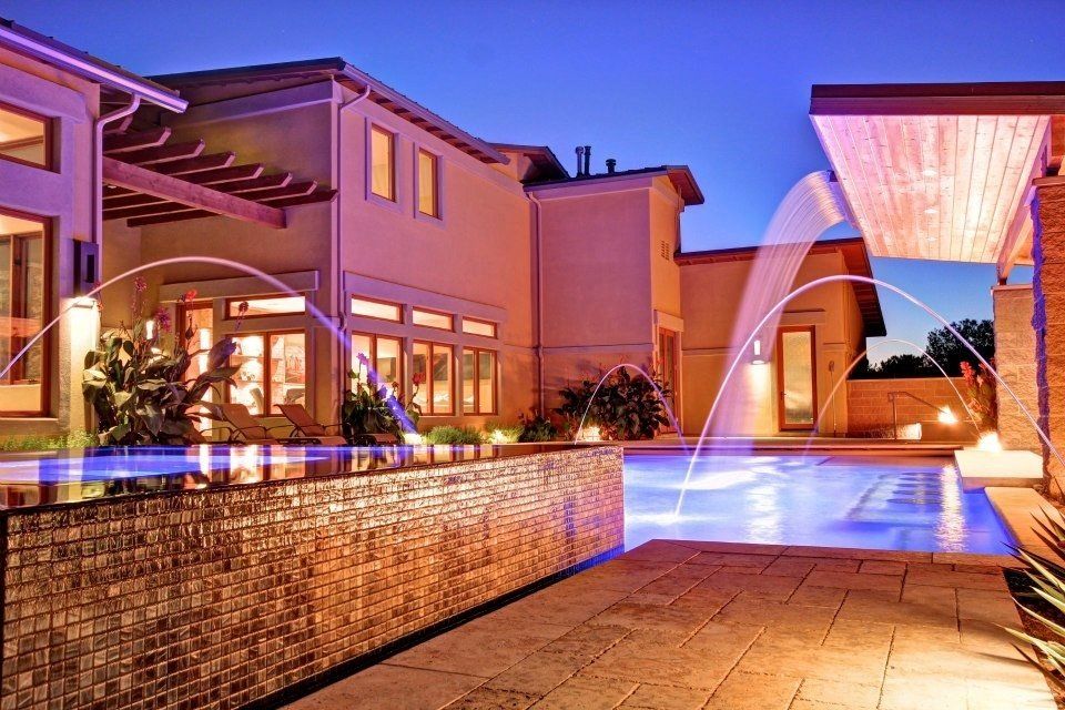 A large house with a swimming pool and fountains in front of it