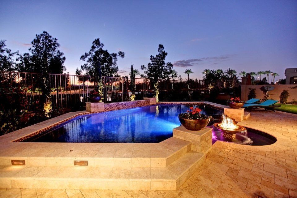 A large swimming pool with a fire pit in the middle at night