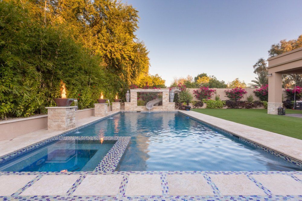 There is a large swimming pool in the backyard of a house.