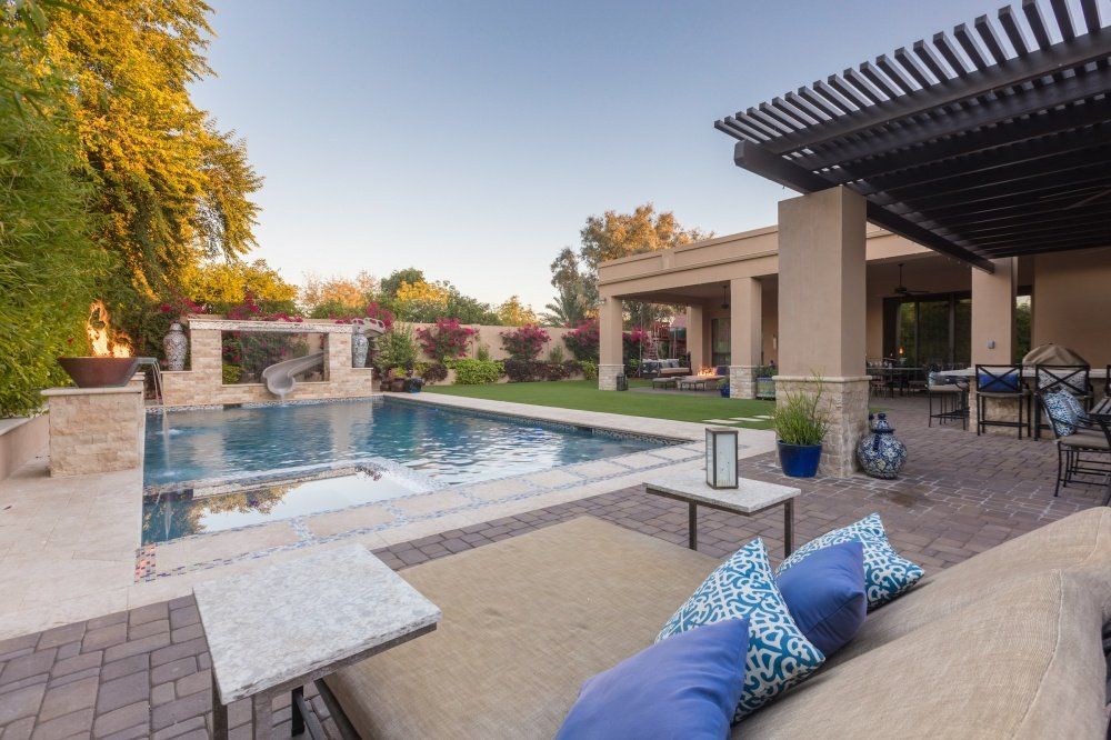 There is a large swimming pool in the backyard of a house.