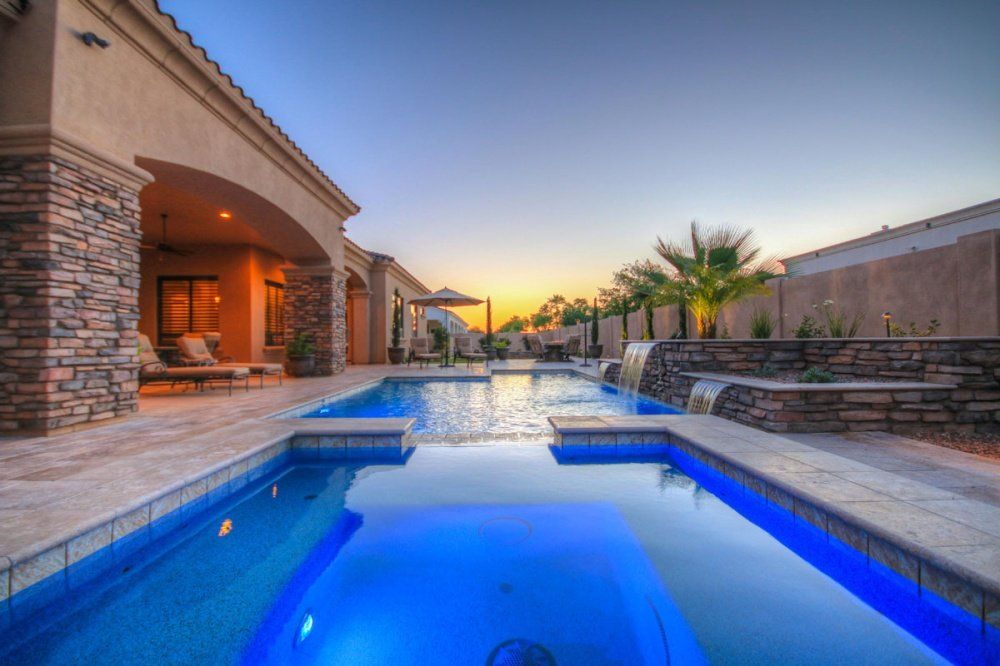 There is a large swimming pool in the backyard of a house.
