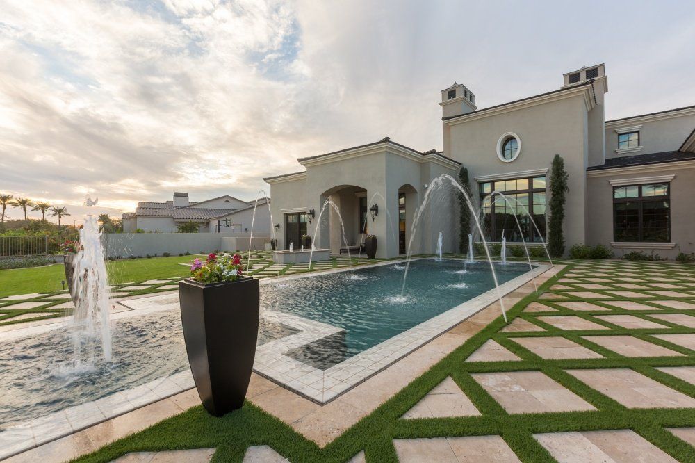 A large house with a swimming pool and a fountain in front of it.