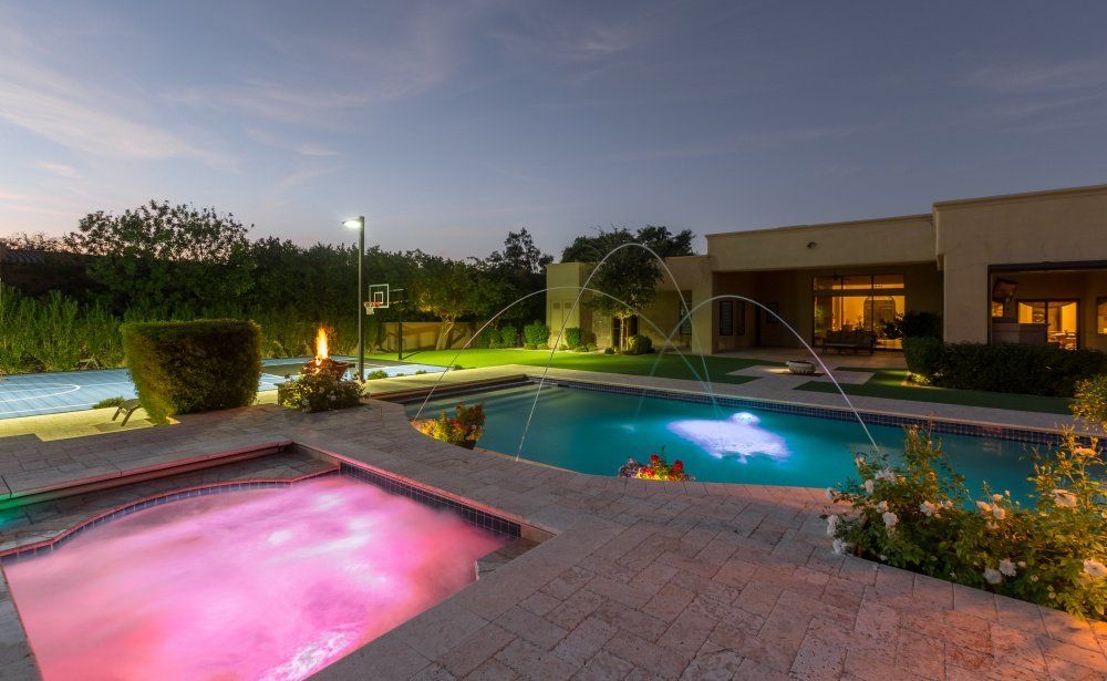 A large swimming pool with a hot tub in front of it.