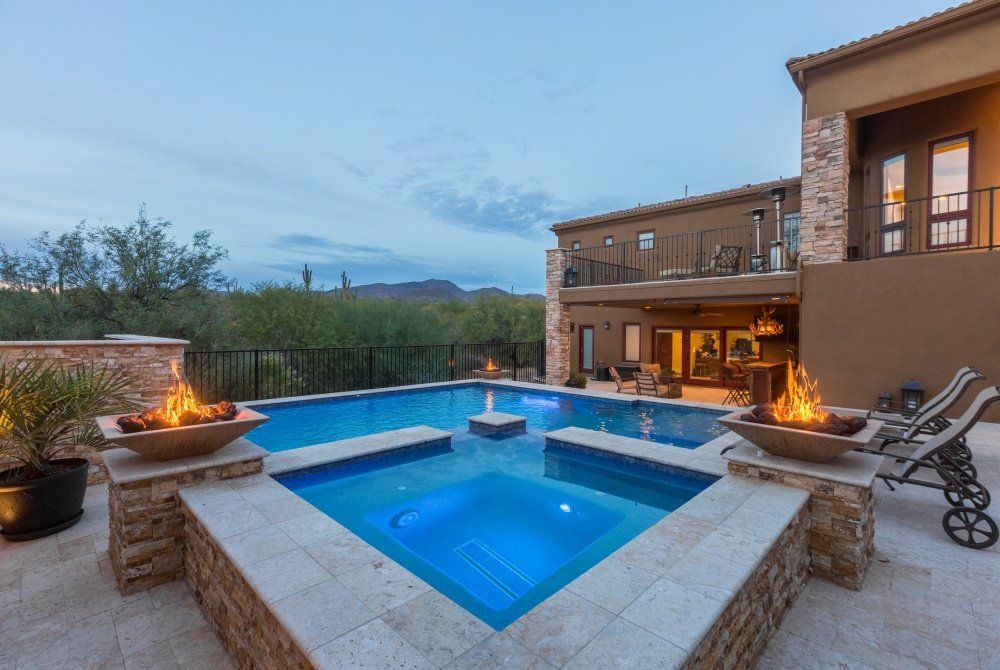 There is a large swimming pool with a fire pit in the middle of it.