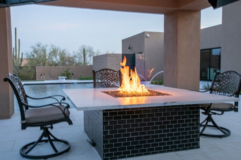 A fire pit is sitting on a patio next to a swimming pool.