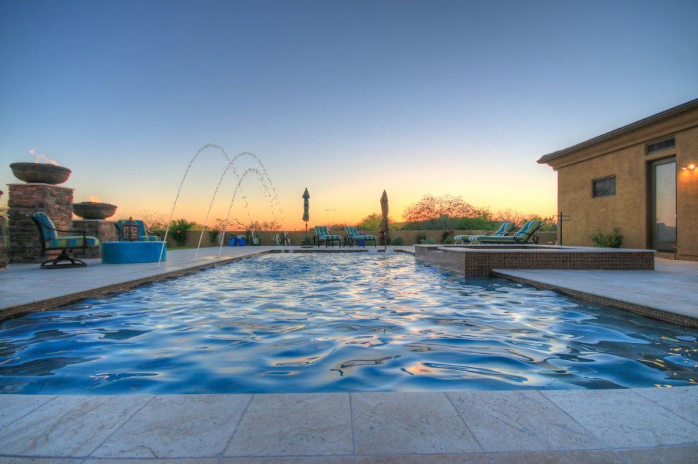 There is a large swimming pool in the backyard of a house.