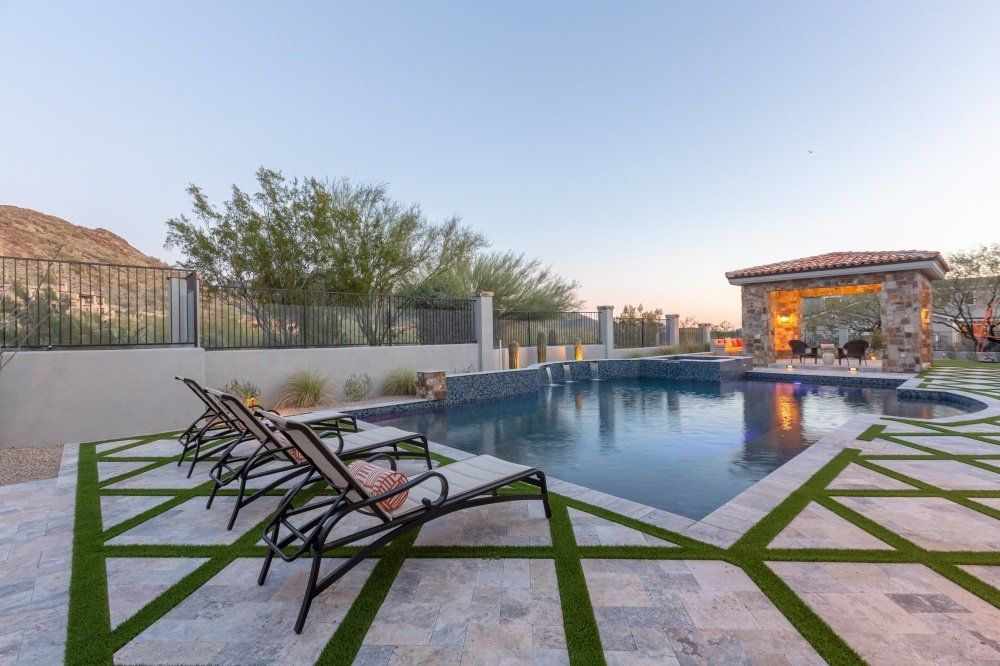 A large swimming pool surrounded by lawn chairs and a gazebo.