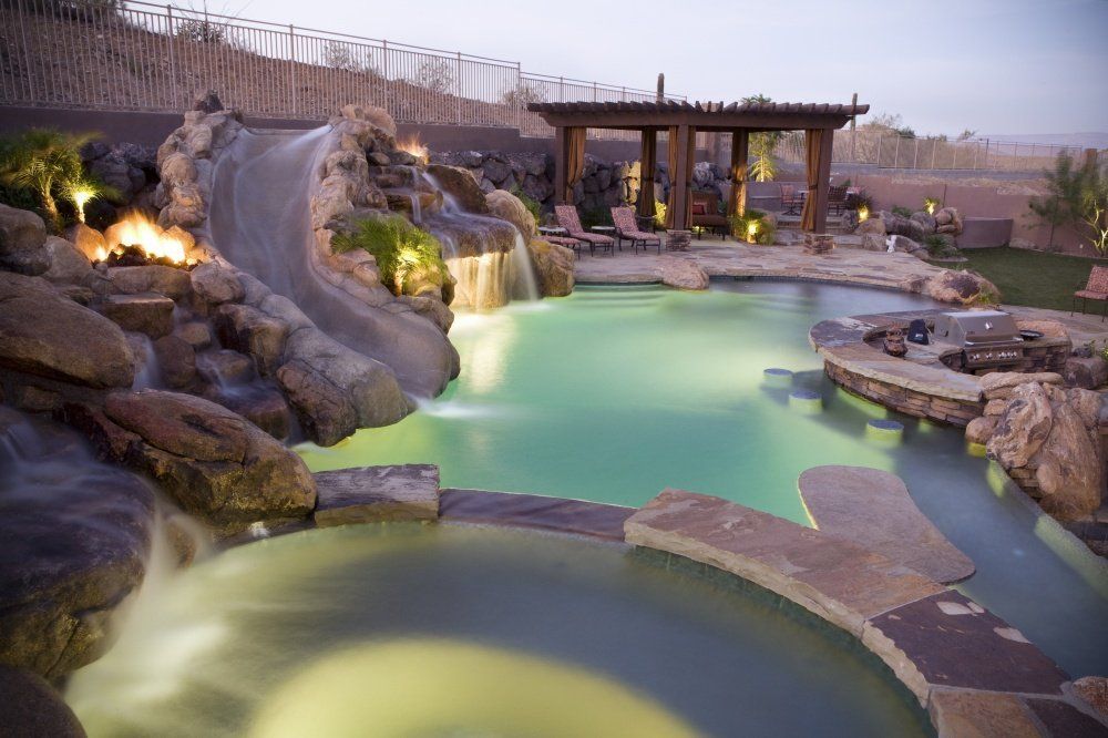 A large swimming pool with a water slide and a fire pit