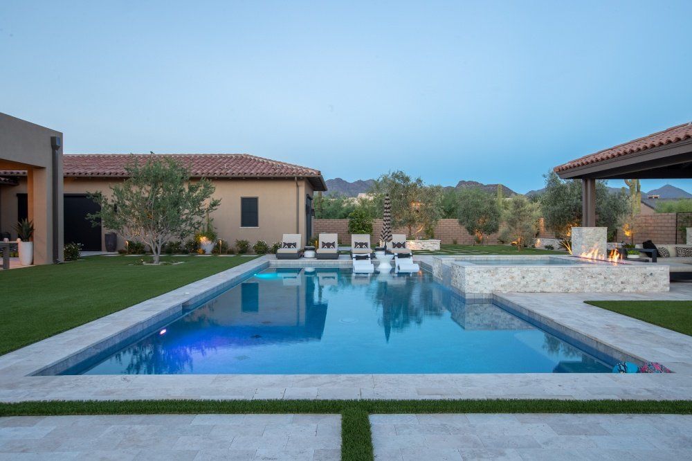 There is a large swimming pool in the backyard of a house.