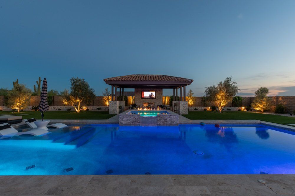 A large swimming pool with a gazebo in the background at night.