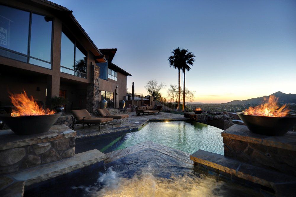 A large house with a swimming pool and fire pits in front of it