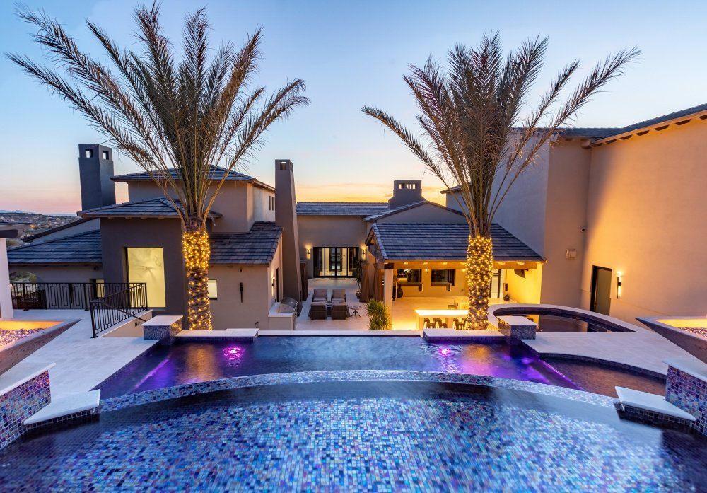 A large house with a swimming pool and palm trees in front of it.