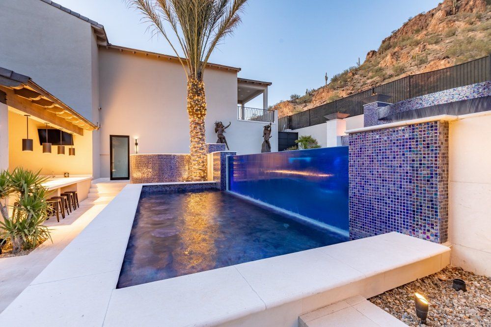 There is a large swimming pool in the backyard of a house.