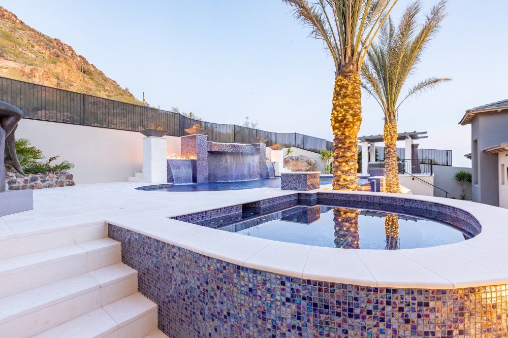 A large swimming pool surrounded by palm trees and stairs in a backyard.