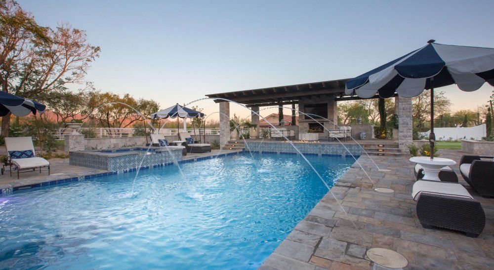 A large swimming pool with umbrellas and chairs around it.