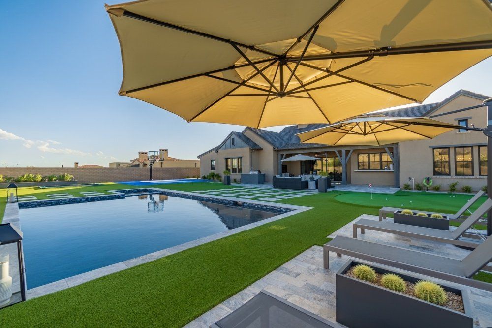 A large swimming pool is surrounded by lawn chairs and umbrellas.
