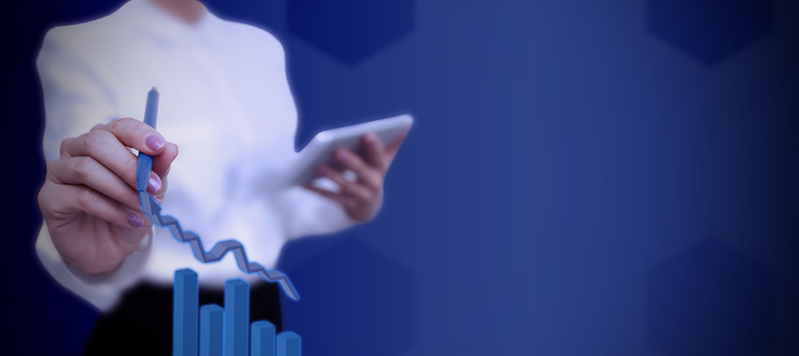 Image of a woman standing behind a stock chart