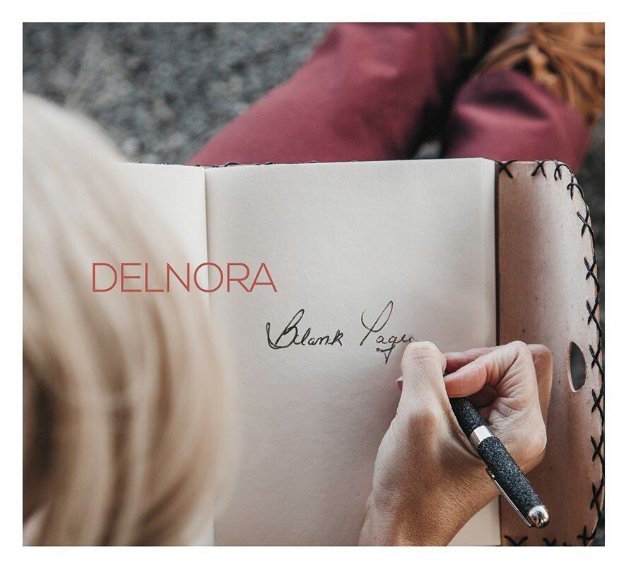 A woman is writing in a notebook with the name delnora on the cover