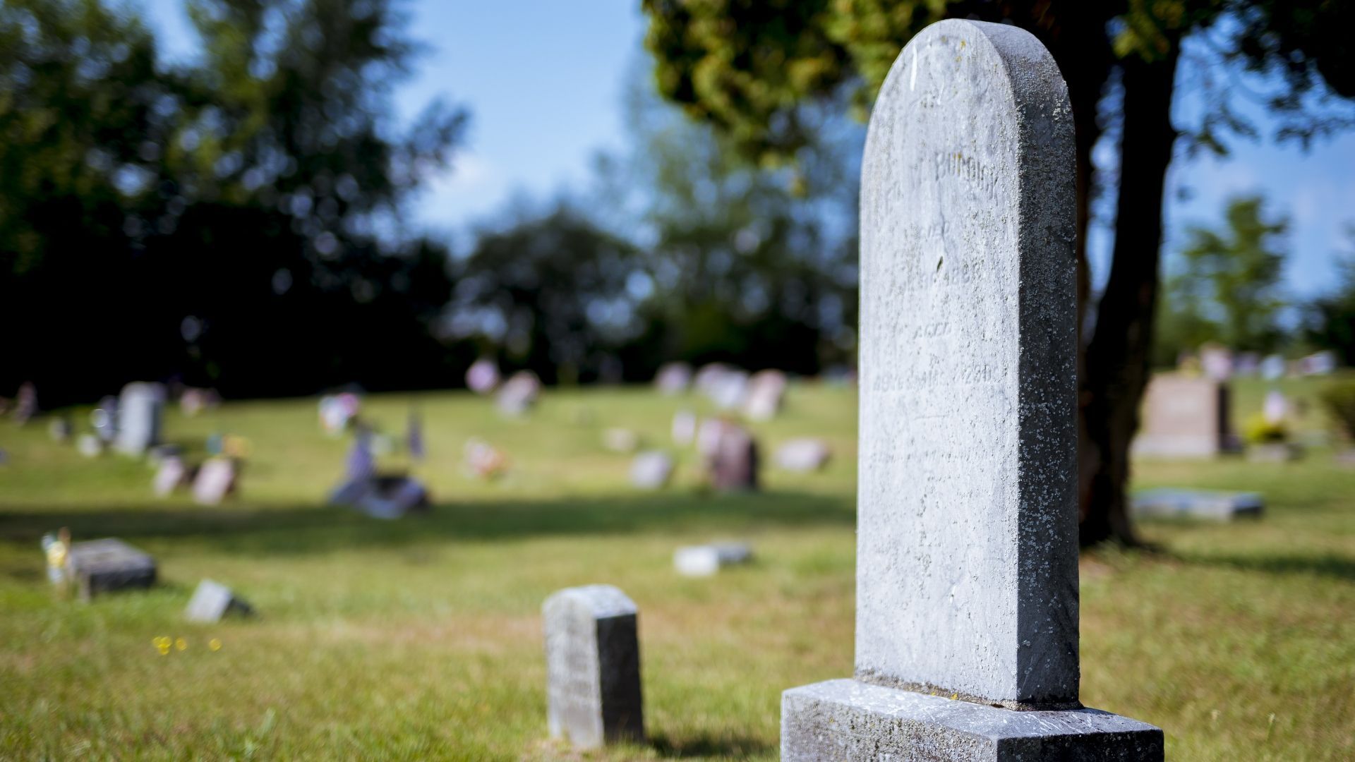 A cemetery with a stone building in the background
