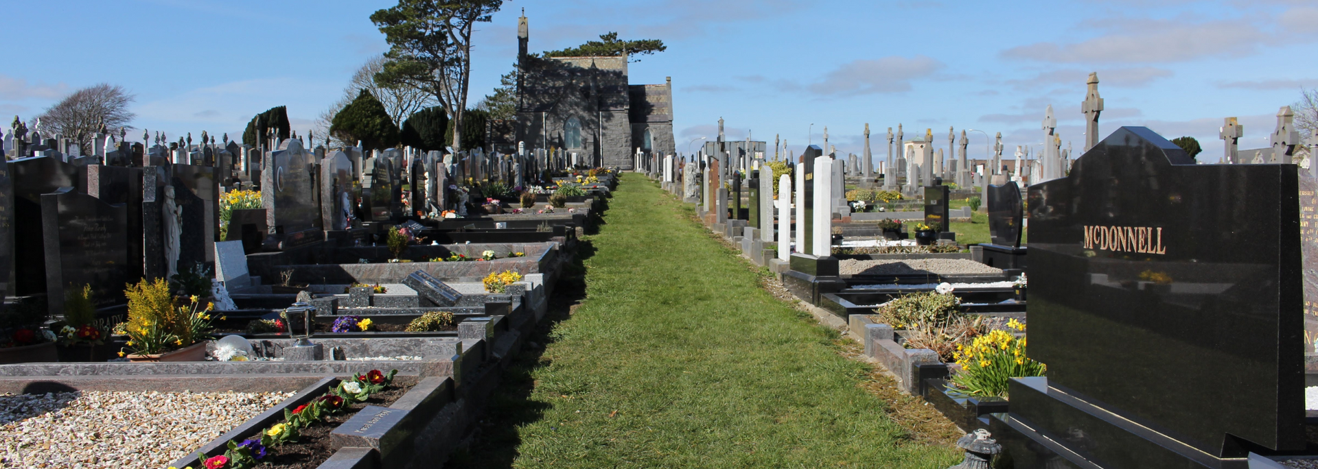Picture of _a line of well-maintained headstones in a cemetery. Picture of _a line of well-maintained headstones in a cemetery.