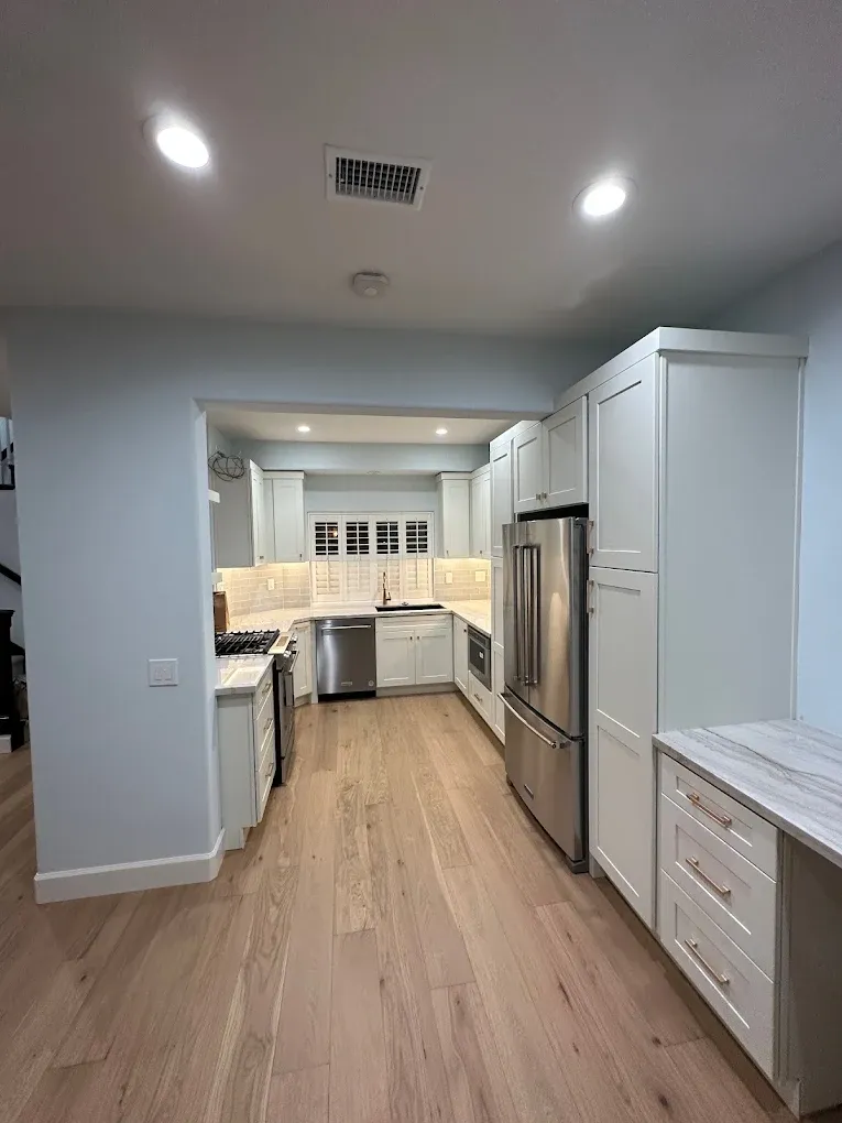 A kitchen with white cabinets , stainless steel appliances , and hardwood floors.