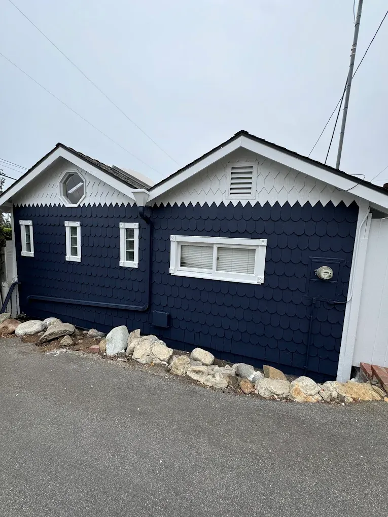 A blue and white house with a clock on the top of it.
