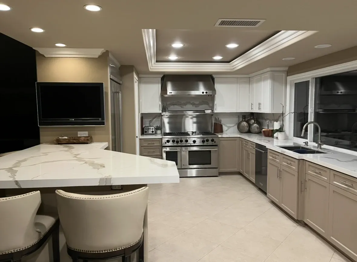 A large kitchen with stainless steel appliances and a flat screen tv.