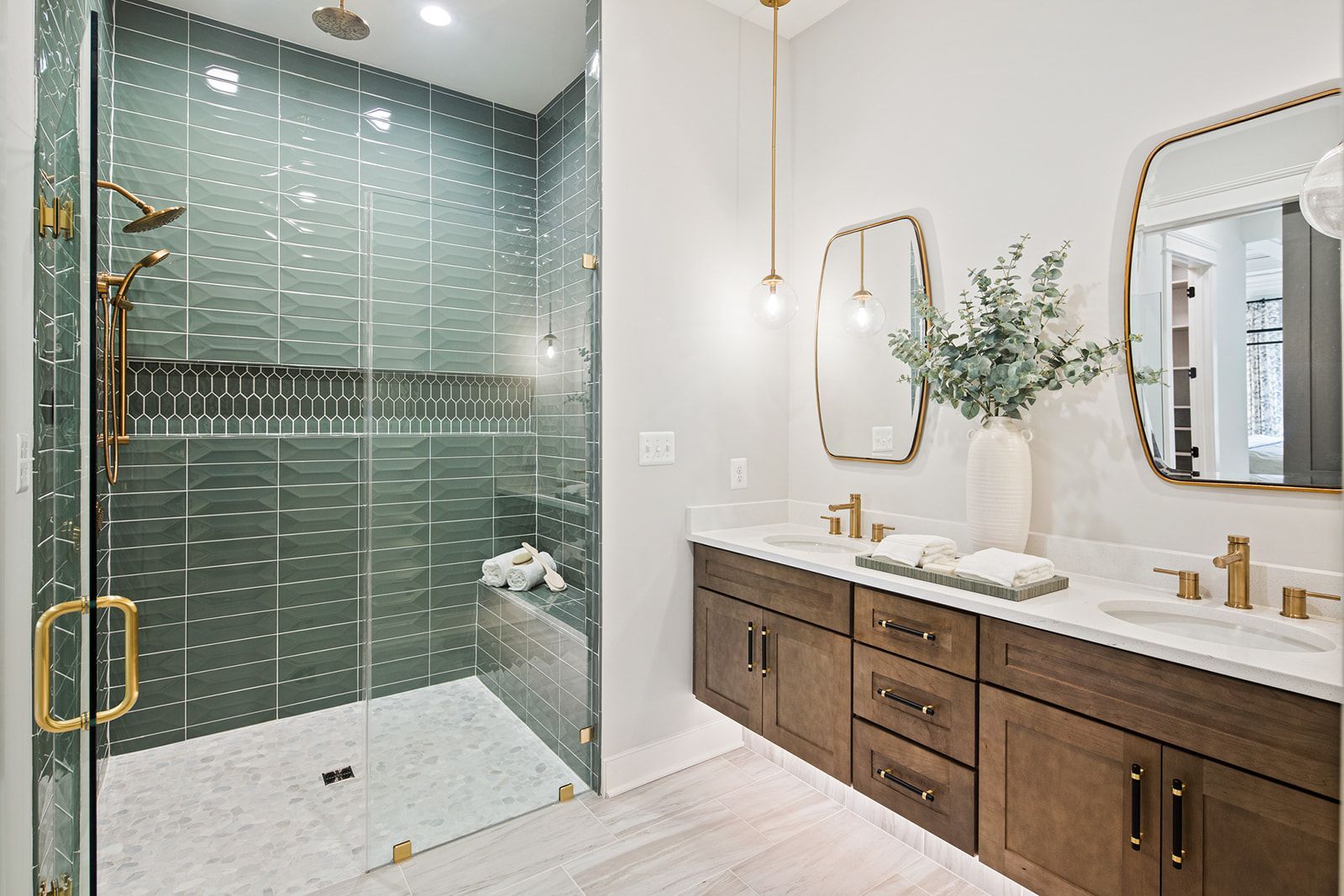 No step bathroom with a green geometric tiled shower, double floating vanity, and gold accents.