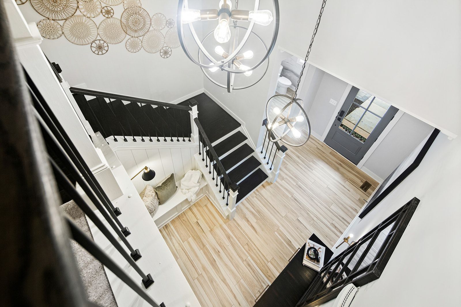 Overhead view of a bright, modern entryway with a staircase and two hanging chandeliers.