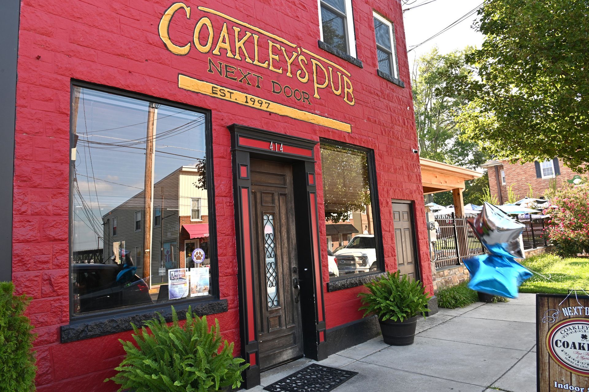 Coakley's Pub with red brick facade, black trim, and large windows; sign above the door; sunny day.
