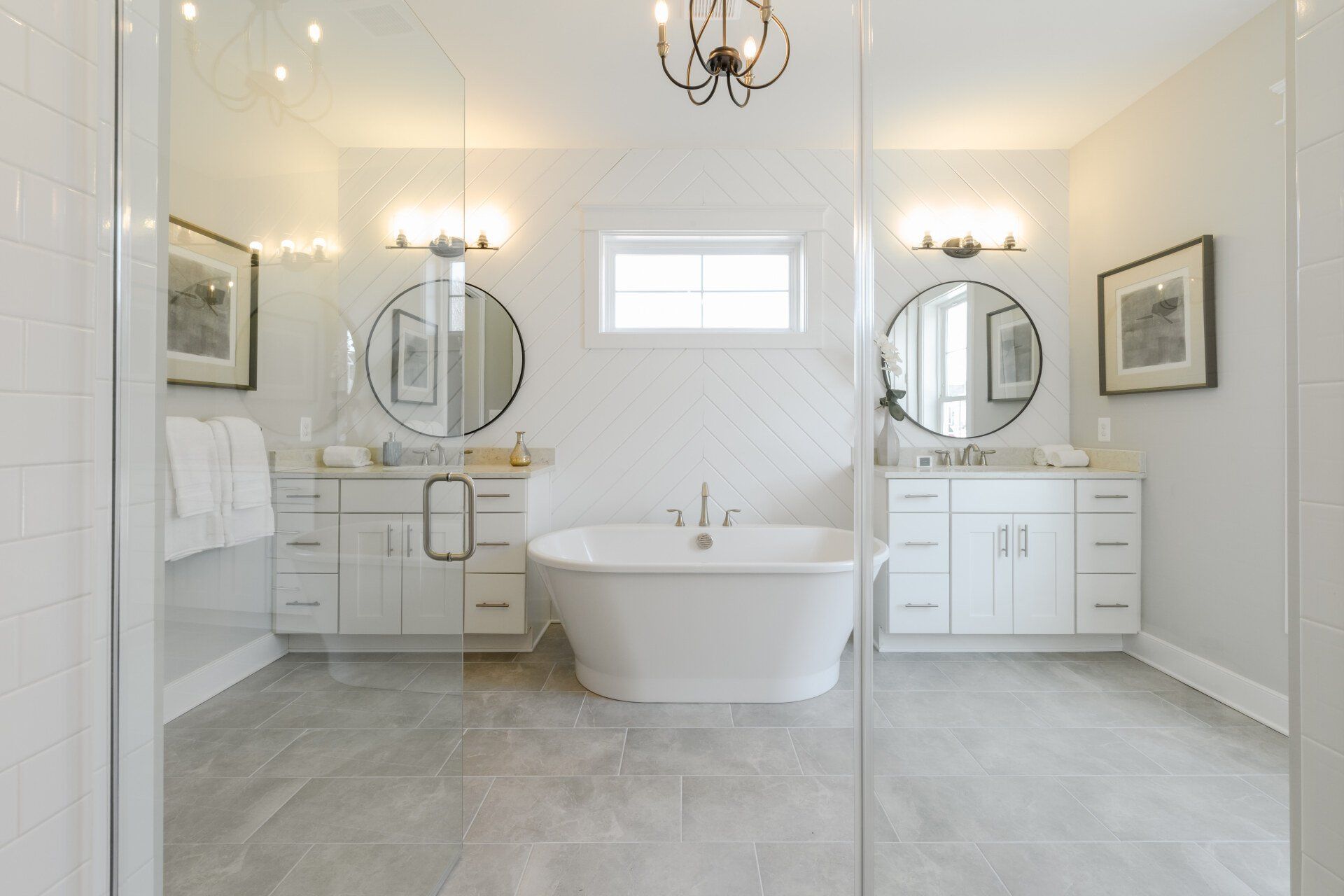 Bright, white bathroom with dual vanities, a freestanding tub, and a glass shower enclosure.