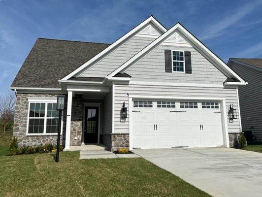 A light gray house with a white garage door and a small lawn, under a blue sky.