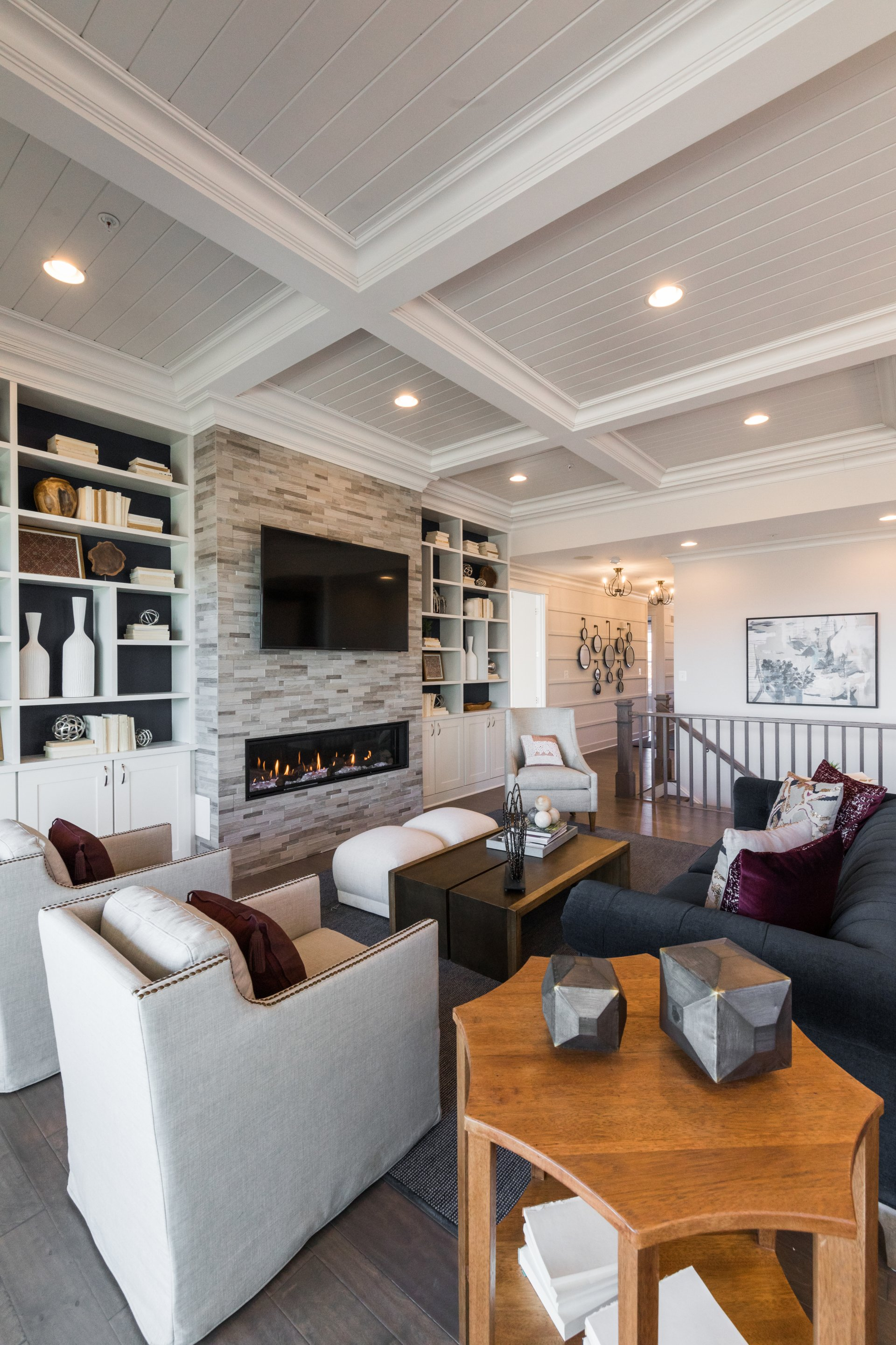 Living room with gray stone fireplace, built-in shelves, white chairs, and a navy sofa.