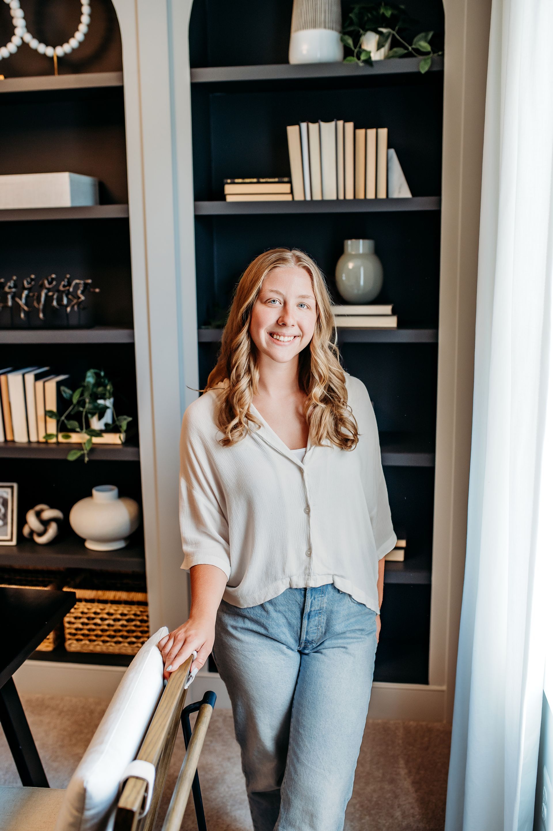Woman smiling in home office with bookshelves.