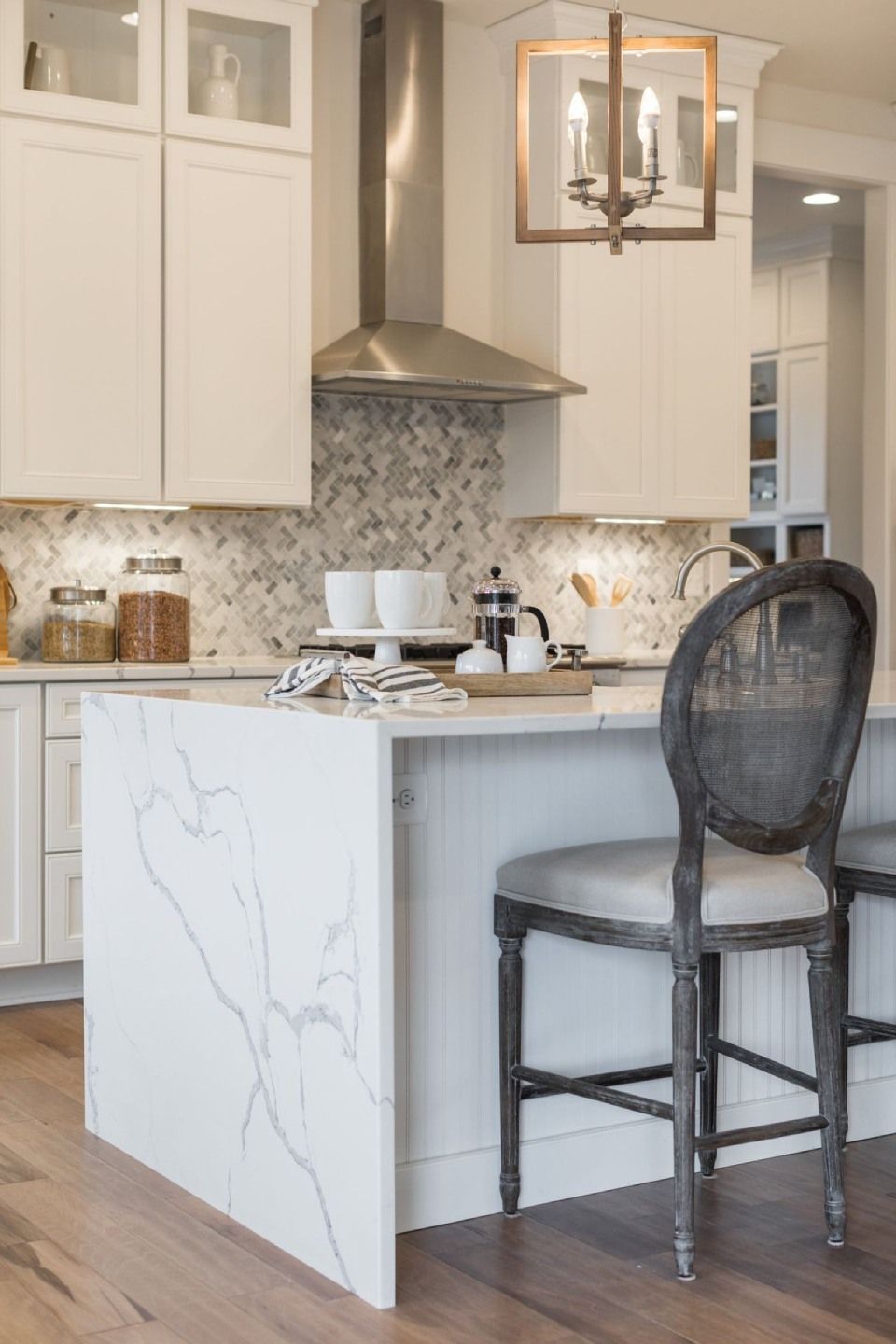 Elegant white kitchen with marble countertops and a dark wooden chair.