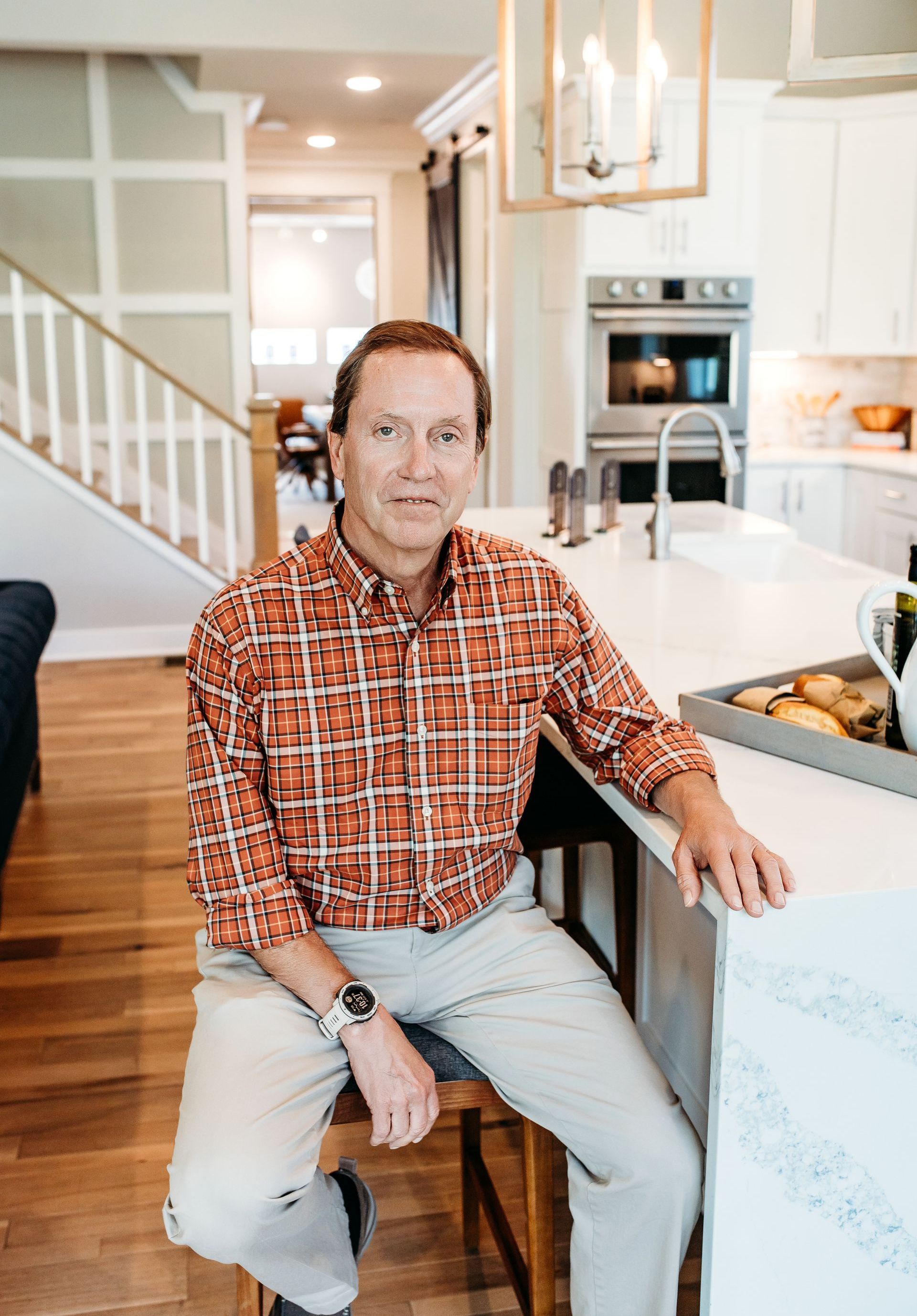 Man in plaid shirt sitting at kitchen island.