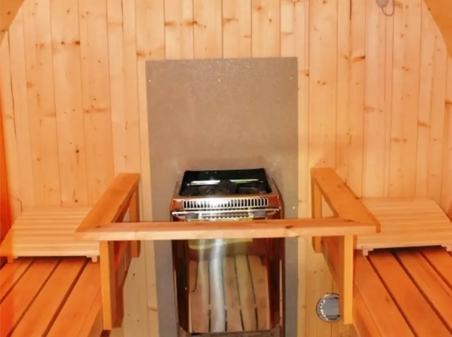 Interieur van een sauna met houten banken en een roestvrijstalen kachel.