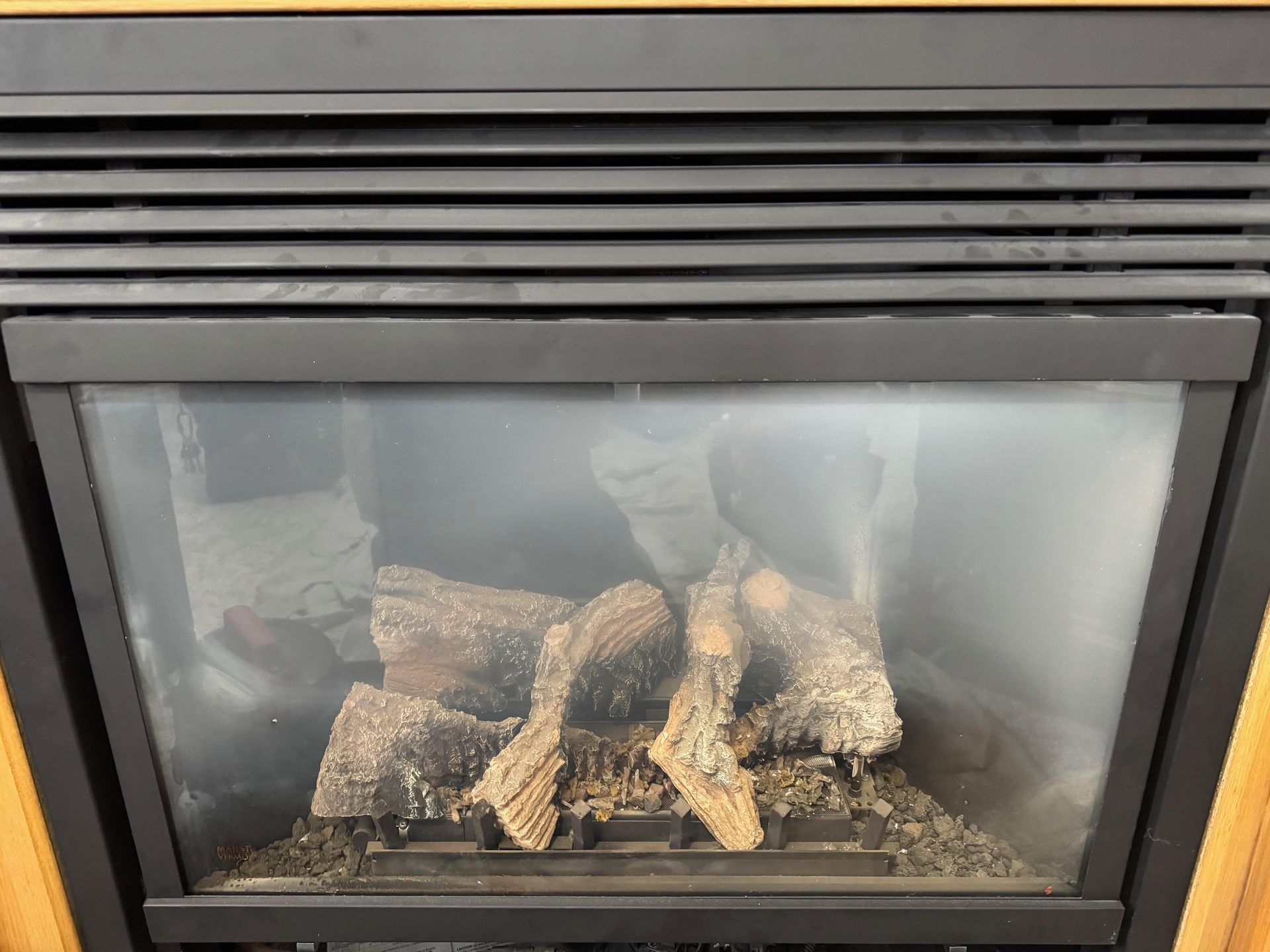 A wood stove with the door open is sitting on a brick floor.
