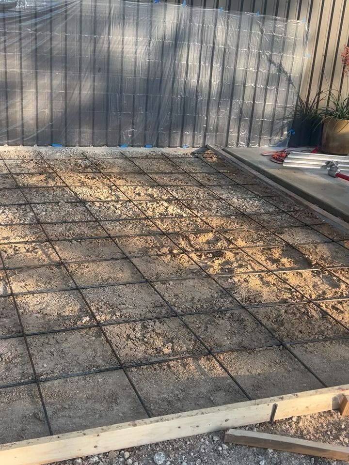 Concrete foundation with rebar grid laid on gravel. Wooden frame visible.